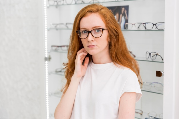 Retrato de mujer atractiva seria mirando a la cámara en la tienda de óptica