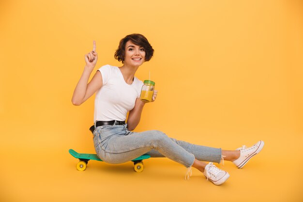 Retrato de una mujer atractiva sonriente sentada en una patineta