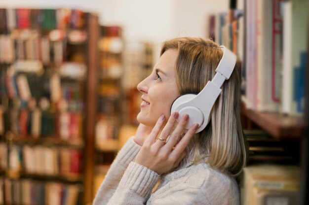 Retrato de mujer con auriculares en la cabeza cerca de estantería