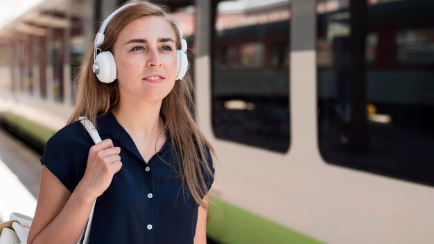 Retrato de mujer con auriculares en la estación de tren