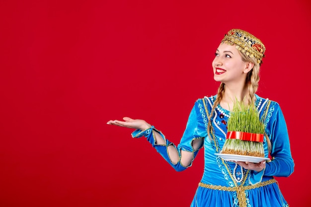 Retrato de mujer azerí en traje tradicional con semeni verde sobre fondo rojo concepto de primavera novruz