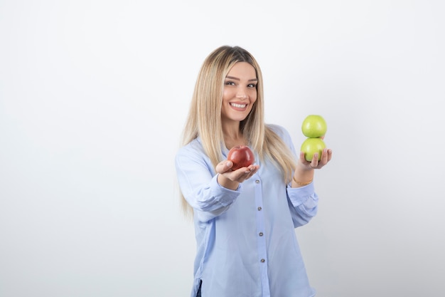 Retrato de una mujer bastante atractiva modelo de pie y sosteniendo manzanas frescas.