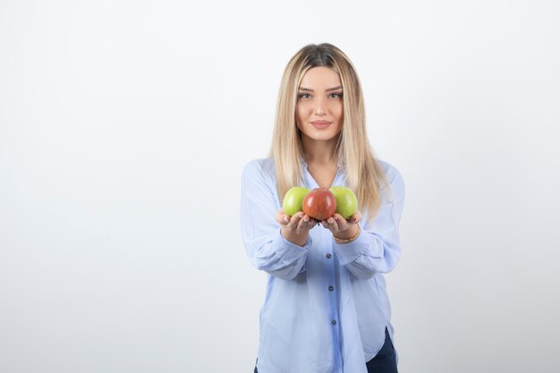 Retrato de una mujer bastante atractiva modelo de pie y sosteniendo manzanas frescas.