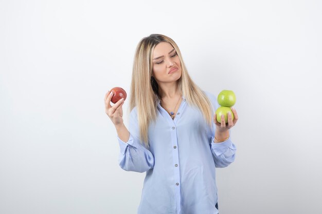 Retrato de una mujer bastante atractiva modelo de pie y sosteniendo manzanas frescas.