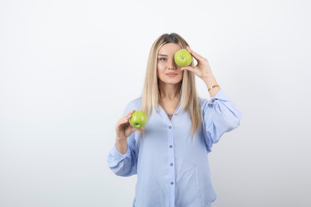 Retrato de una mujer bastante atractiva modelo de pie y sosteniendo manzanas frescas.