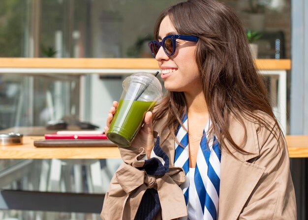 Retrato de mujer bebiendo batido verde