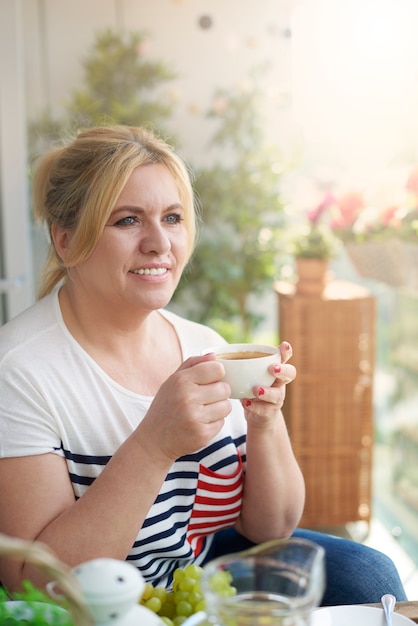 Retrato de mujer bebiendo café en el balcón de cerca