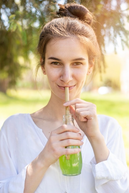 Retrato de mujer bebiendo jugo de botella de vidrio