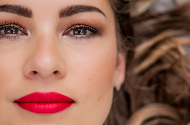 Retrato De La Mujer De La Belleza. Maquillaje profesional para morena con ojos verdes - lápiz labial rojo, ojos ahumados. Muchacha Hermosa Del Modelo De Manera. Piel perfecta. Maquillaje. Aislado en un fondo blanco. Parte de la cara