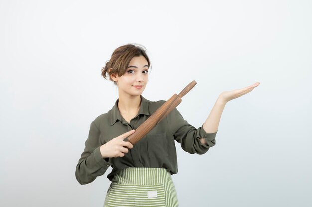 Retrato de mujer bonita en delantal sosteniendo un rodillo. foto de alta calidad