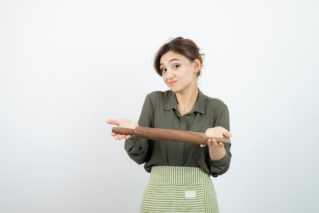 Retrato de mujer bonita en delantal sosteniendo un rodillo. foto de alta calidad