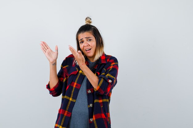 Retrato de mujer bonita fingiendo mostrar algo en ropa casual y mirando perplejo