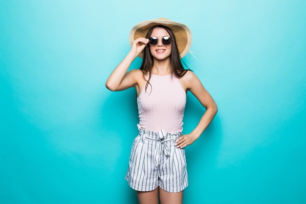 Retrato de mujer bonita con gafas de sol y sombrero sobre pared de colores azul. Vocación de verano.