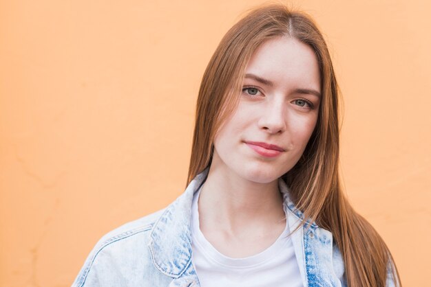 Retrato de la mujer bonita joven contra fondo beige