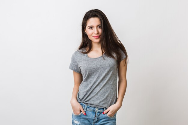 Retrato de mujer bonita joven con estilo sonriendo en camiseta gris, mirada aislada, natural, cabello largo castaño, jeans, estilo sexy y casual