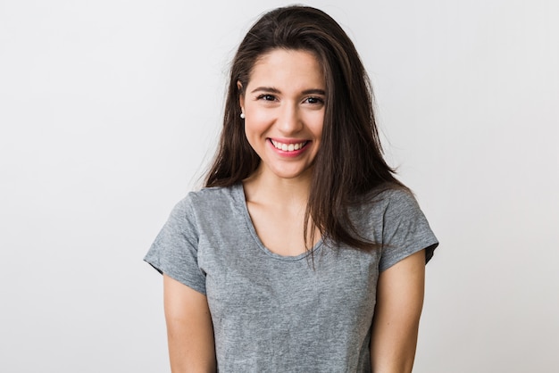 Retrato de mujer bonita joven con estilo sonriendo en camiseta gris, mirada aislada, natural, largo cabello castaño, sonrisa sincera