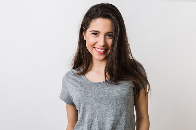 Retrato de mujer bonita joven con estilo sonriendo en camiseta gris, mirada aislada, natural, largo cabello castaño, sonrisa sincera