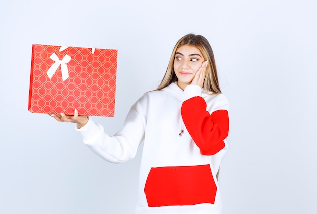 Retrato de mujer bonita modelo de pie y mostrando bolsa de regalo