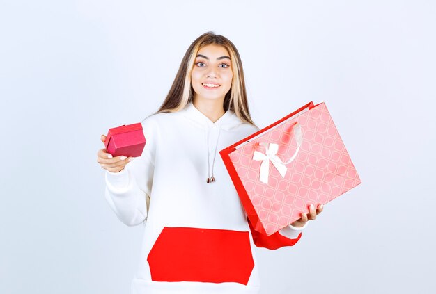 Retrato de mujer bonita modelo de pie y sosteniendo la bolsa con caja pequeña