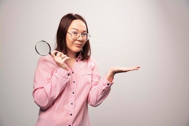 Retrato de mujer bonita en ropa rosa sosteniendo una lupa. Foto de alta calidad