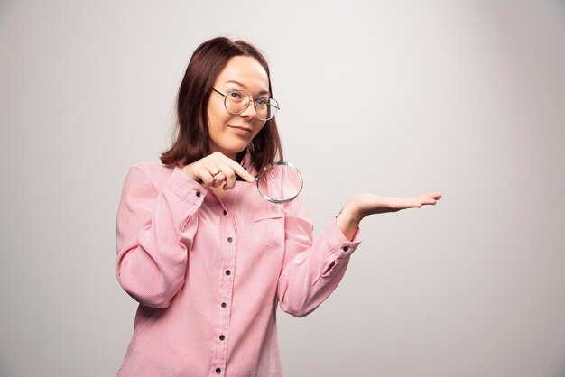 Retrato de mujer bonita en ropa rosa sosteniendo una lupa. Foto de alta calidad