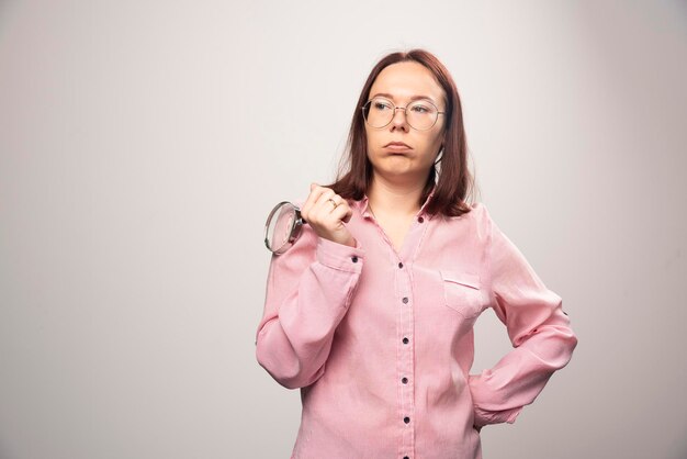 Retrato de mujer bonita en ropa rosa sosteniendo una lupa. Foto de alta calidad