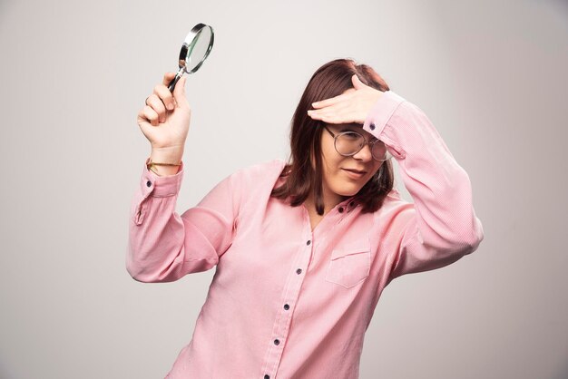 Retrato de mujer bonita en ropa rosa sosteniendo una lupa. Foto de alta calidad