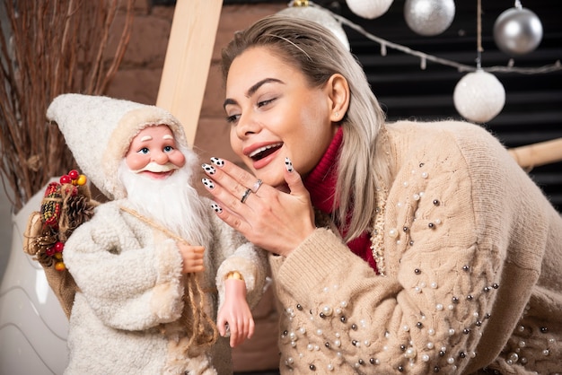 Retrato de mujer bonita sentada con juguete de Santa Claus Foto de alta calidad