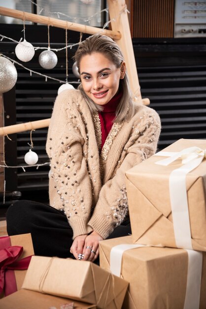 Retrato de mujer bonita sentada con regalos de Navidad