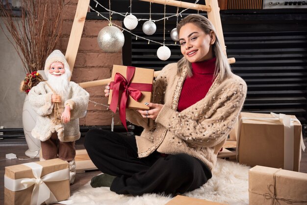 Retrato de mujer bonita sentada y sosteniendo un regalo de Navidad