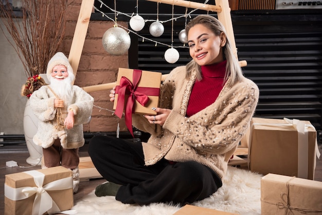 Retrato de mujer bonita sentada y sosteniendo un regalo de Navidad