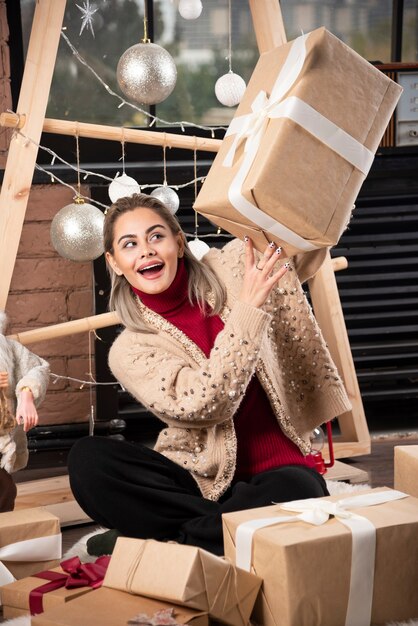 Retrato de mujer bonita sentada y sosteniendo un regalo de Navidad