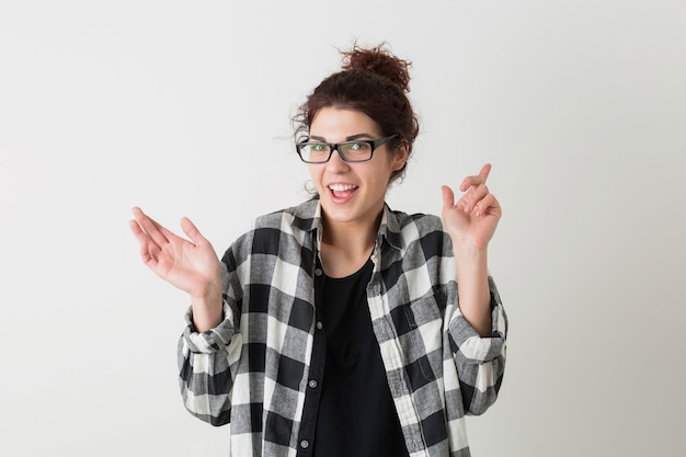 Retrato de mujer bonita sonriente joven inconformista en camisa a cuadros con expresión de la cara divertida con gafas posando aislado sobre fondo blanco de estudio, emocional