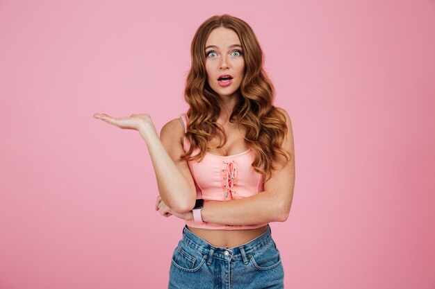 Retrato de una mujer bonita sorprendida en ropa de verano señalando