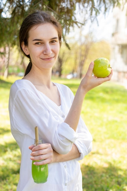 Retrato de mujer con botella de jugo y manzana