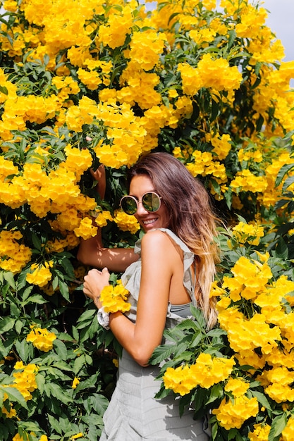 Retrato de mujer bronceada en vestido y gafas de sol