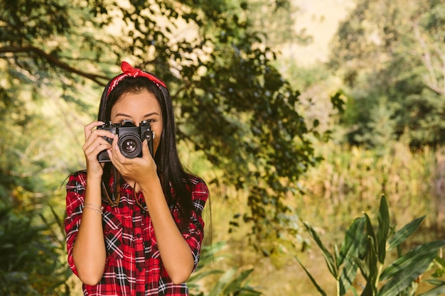 Retrato de una mujer con cámara en el bosque