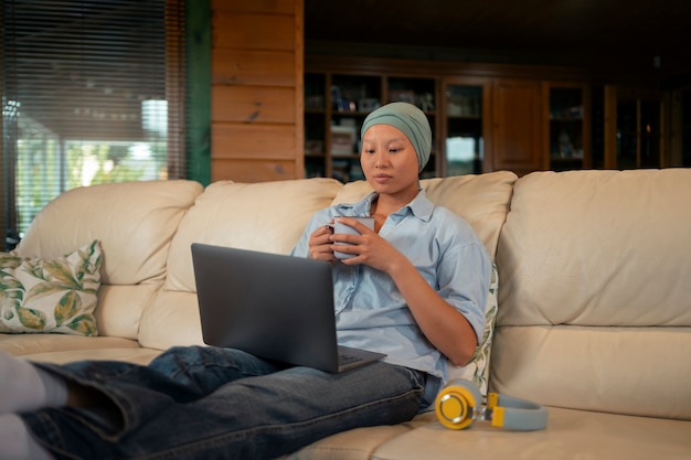 Foto gratuita retrato de una mujer con cáncer usando su computadora portátil en casa