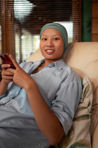 Retrato de una mujer con cáncer usando su teléfono inteligente en casa