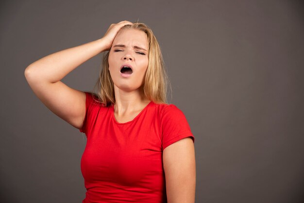 Retrato de mujer cansada tocando su cabeza sobre la oscuridad.