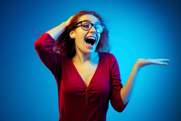 Retrato de mujer caucásica aislado en espacio azul en luz de neón