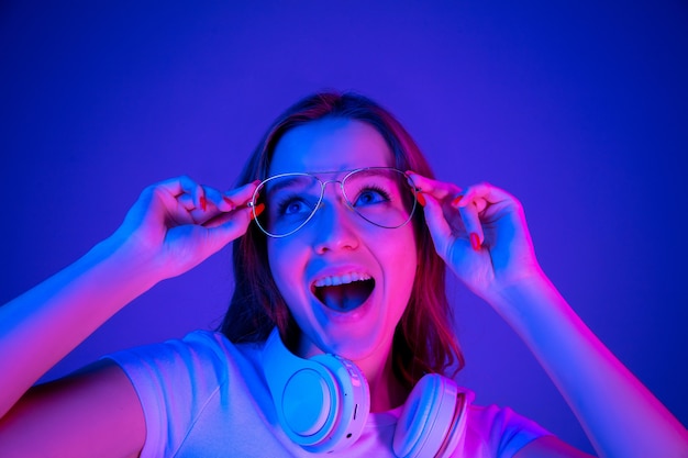 Retrato de mujer caucásica aislado sobre fondo azul en luz de neón multicolor.