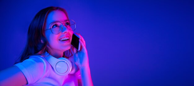 Retrato de mujer caucásica aislado sobre fondo azul en luz de neón multicolor.