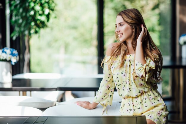 Retrato de mujer caucásica rubia atractiva, modelo, almorzar en la terraza del café y mirando hacia adelante