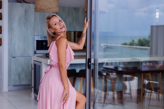 Retrato de mujer caucásica en vestido largo rosa elegante romántico de vacaciones en el lujoso hotel villa rica con increíbles palmeras tropicales vista Mujer en sombrero blanco clásico