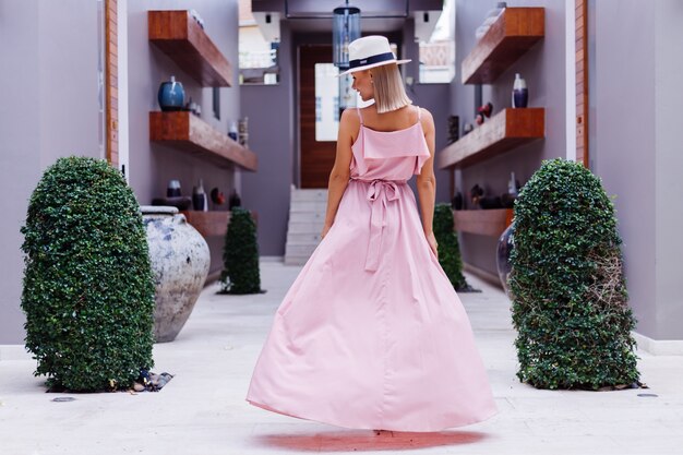 Retrato de mujer caucásica en vestido largo rosa elegante romántico de vacaciones en el lujoso hotel villa rica con increíbles palmeras tropicales vista Mujer con sombrero blanco clásico