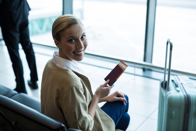 Retrato de mujer de cercanías con pasaporte y tarjeta de embarque en la sala de espera