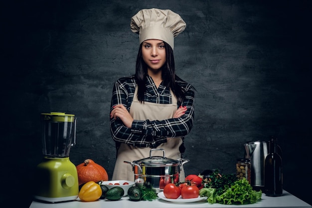 Foto gratuita retrato de mujer chef con una olla en la mesa con verduras frescas.