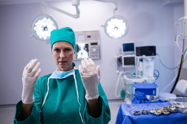 Retrato de mujer cirujana con guantes quirúrgicos en quirófano