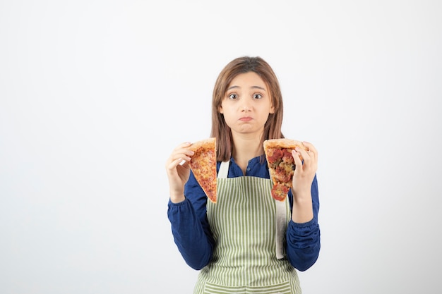 Retrato de mujer cocinera en delantal sosteniendo pizza en blanco